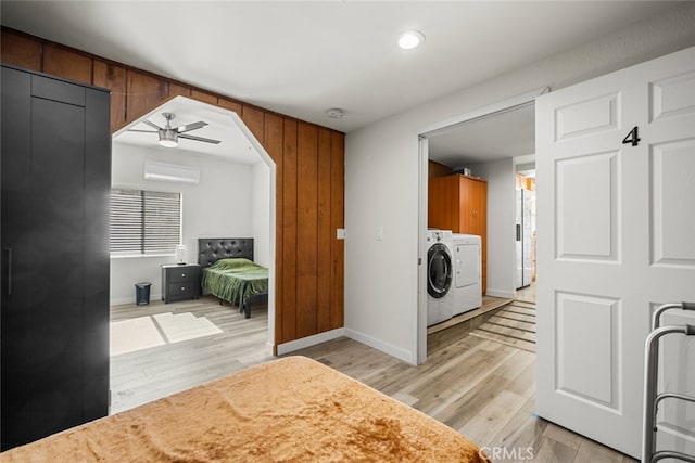 laundry room with separate washer and dryer, a wall mounted AC, cabinets, ceiling fan, and light wood-type flooring