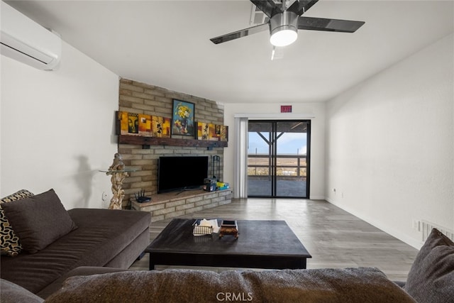 living room featuring ceiling fan, a wall mounted AC, hardwood / wood-style floors, and a brick fireplace