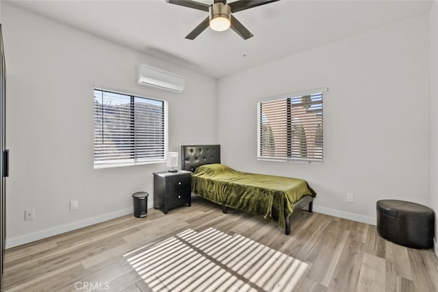 bedroom with a wall mounted air conditioner, ceiling fan, and light hardwood / wood-style flooring