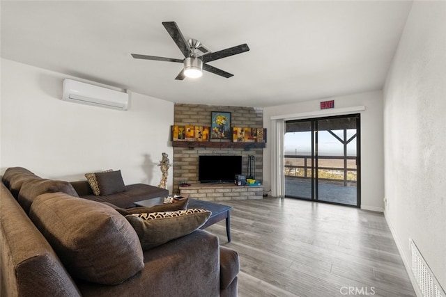 living room with hardwood / wood-style floors, a fireplace, an AC wall unit, and ceiling fan