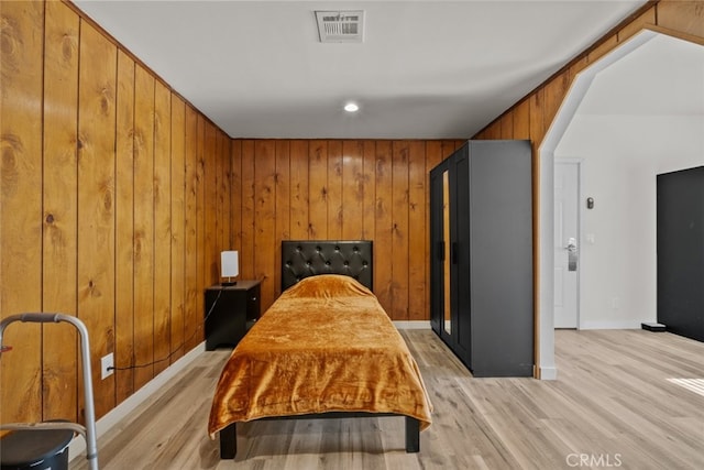 bedroom featuring light wood-type flooring and wood walls