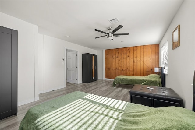 bedroom with hardwood / wood-style floors, wooden walls, elevator, and ceiling fan