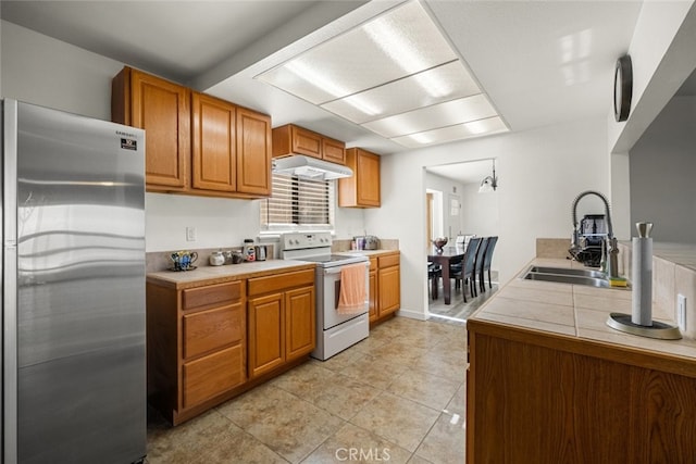 kitchen with sink, light tile patterned flooring, stainless steel refrigerator, and white range with electric cooktop