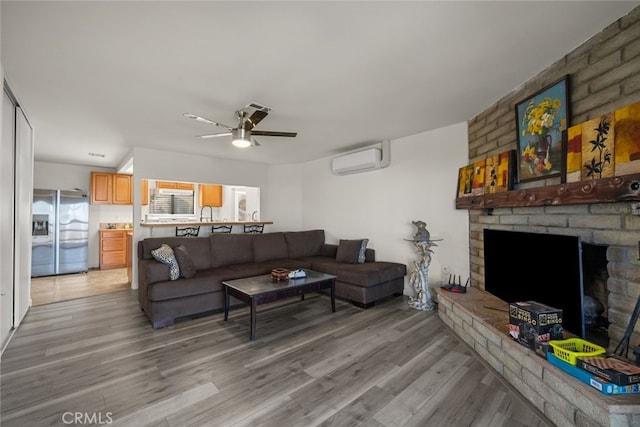 living room with a fireplace, light hardwood / wood-style floors, an AC wall unit, and ceiling fan