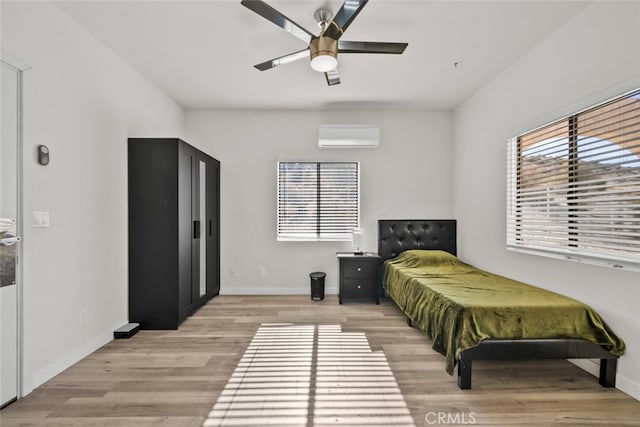 bedroom featuring ceiling fan, a wall mounted AC, and light wood-type flooring