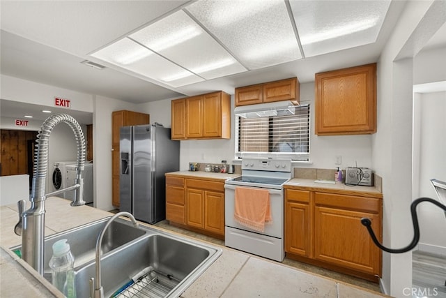 kitchen with electric stove, stainless steel fridge, and sink