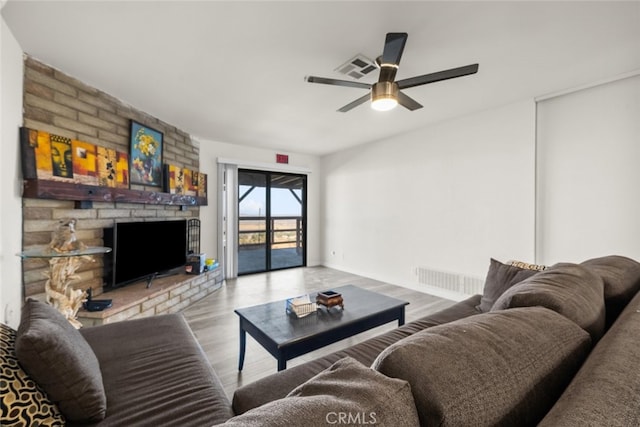 living room with a large fireplace, ceiling fan, and light hardwood / wood-style flooring