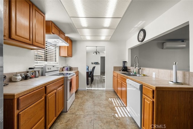 kitchen with tile countertops, wall chimney range hood, a wall mounted AC, and white appliances