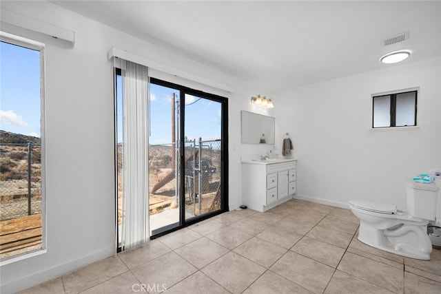 bathroom featuring a healthy amount of sunlight, toilet, tile patterned flooring, and vanity