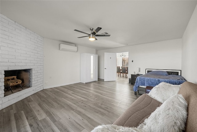 bedroom with ceiling fan, wood-type flooring, a wall mounted AC, and a brick fireplace