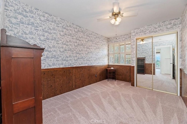 unfurnished room with carpet flooring, a fireplace, ceiling fan, and wood walls