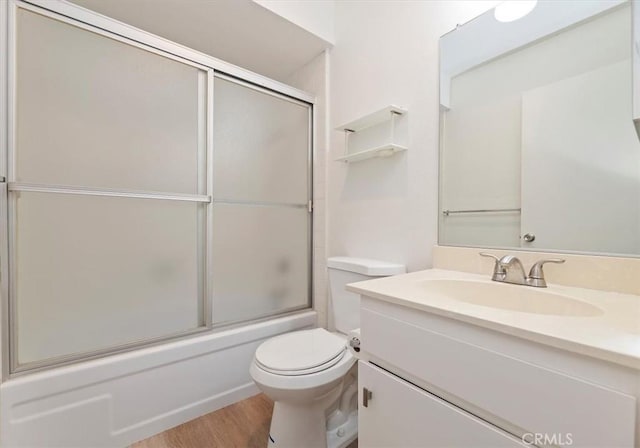 full bathroom with toilet, vanity, bath / shower combo with glass door, and hardwood / wood-style flooring