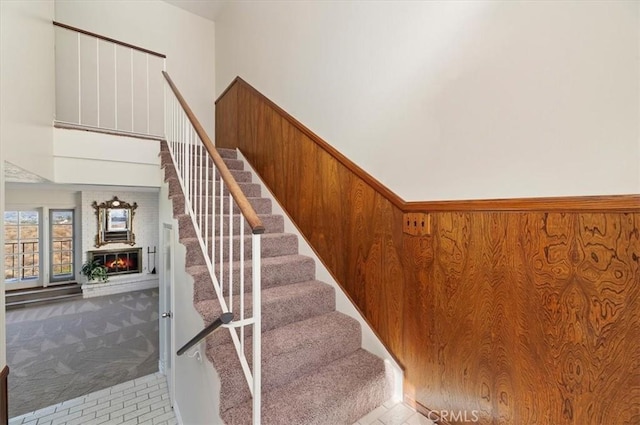 staircase featuring a towering ceiling, carpet floors, and wood walls