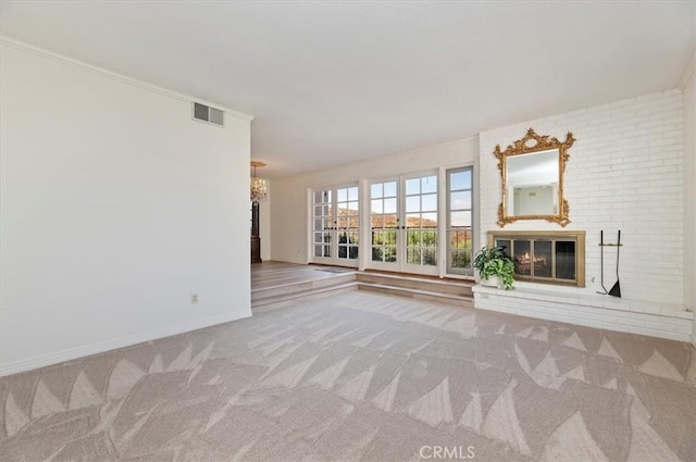 unfurnished living room with a notable chandelier, a fireplace, ornamental molding, and carpet flooring