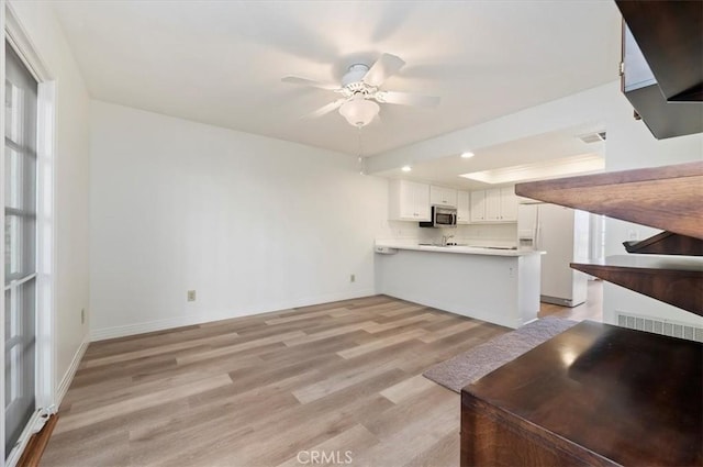 unfurnished living room featuring ceiling fan and light wood-type flooring