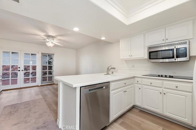 kitchen with sink, stainless steel appliances, kitchen peninsula, and white cabinets