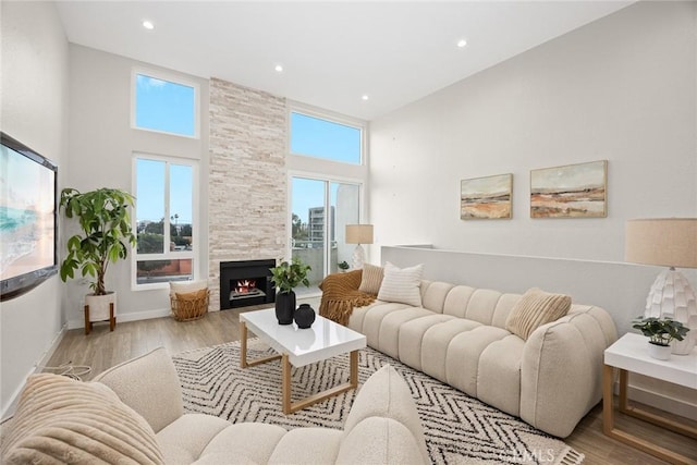 living room with a large fireplace, light hardwood / wood-style flooring, and a towering ceiling