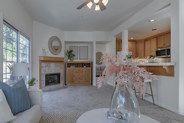 living room with light colored carpet, a tile fireplace, and ceiling fan