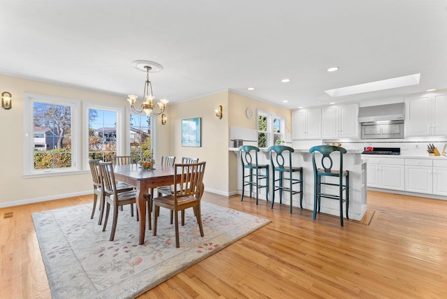 dining room with a chandelier, a wealth of natural light, and light hardwood / wood-style floors