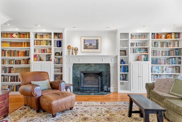 sitting room with a fireplace, light hardwood / wood-style floors, and built in features