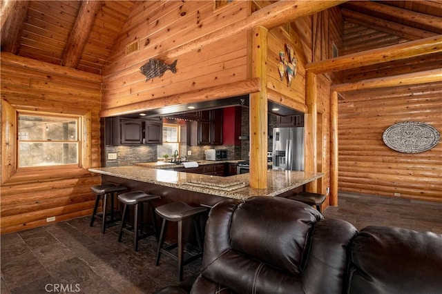 kitchen featuring plenty of natural light, high vaulted ceiling, a kitchen bar, and stainless steel refrigerator with ice dispenser