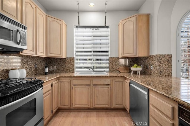 kitchen with sink, stainless steel appliances, light stone counters, tasteful backsplash, and light brown cabinetry