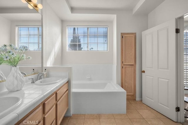 bathroom with tile patterned flooring, vanity, and tiled bath