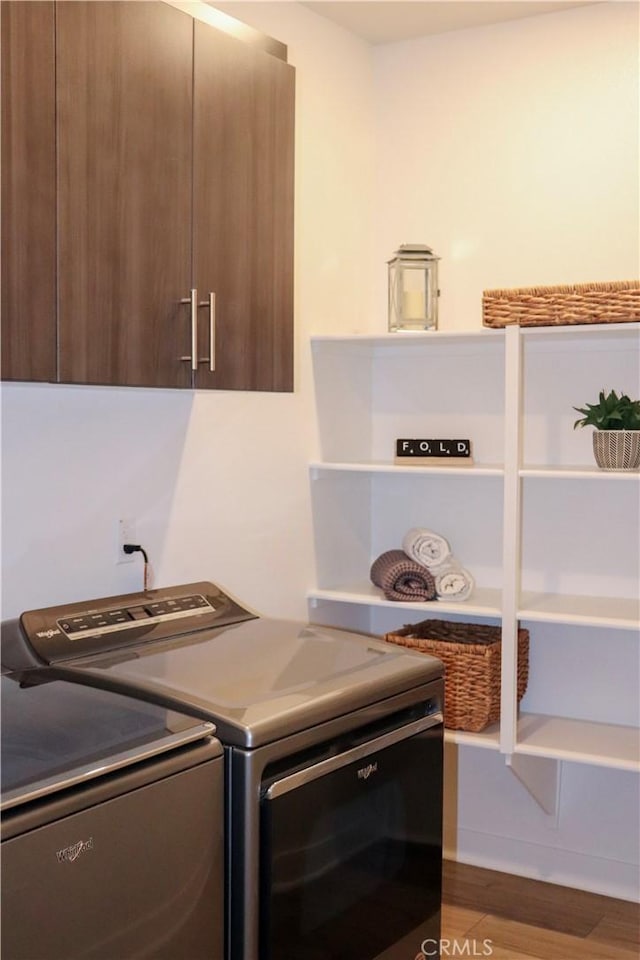 laundry area featuring separate washer and dryer, hardwood / wood-style floors, and cabinets