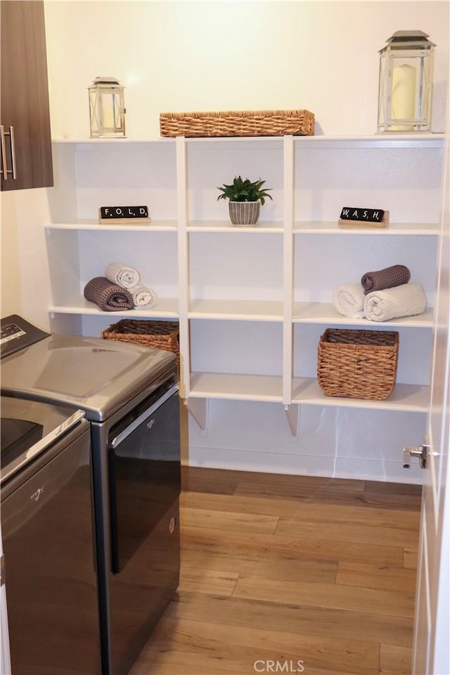 clothes washing area with separate washer and dryer and light hardwood / wood-style floors