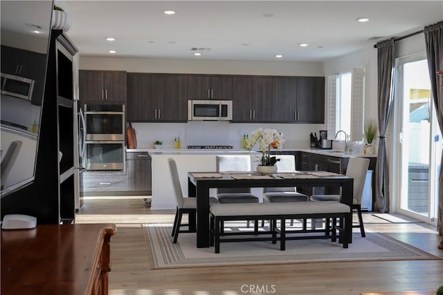 kitchen featuring dark brown cabinetry, stainless steel appliances, sink, and light wood-type flooring