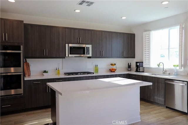 kitchen featuring a healthy amount of sunlight, stainless steel appliances, a center island, and sink