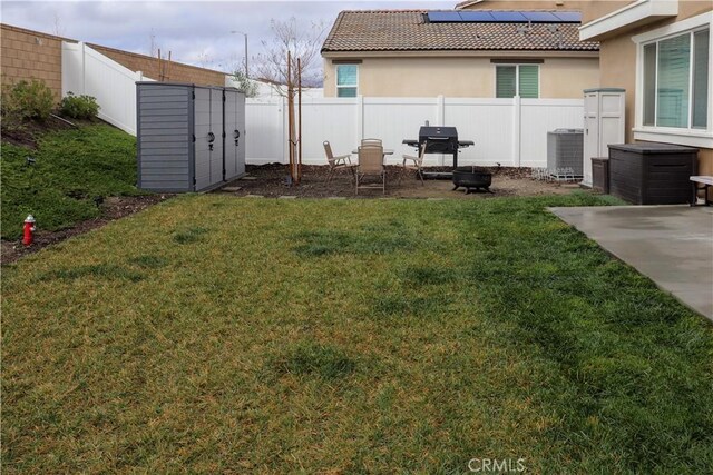 view of yard with a fire pit, a patio, central air condition unit, and a storage unit