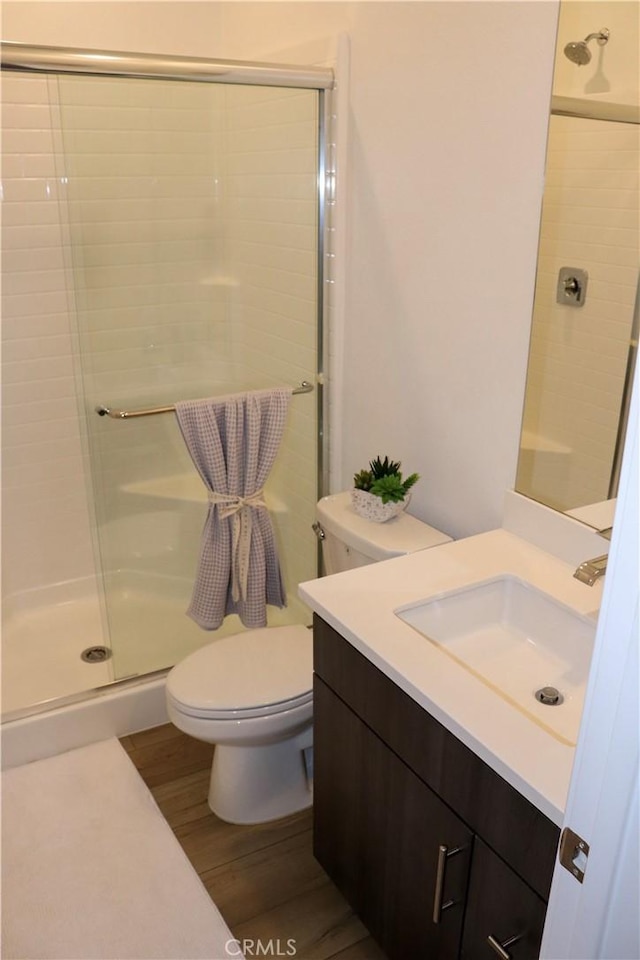 bathroom with hardwood / wood-style flooring, vanity, toilet, and walk in shower