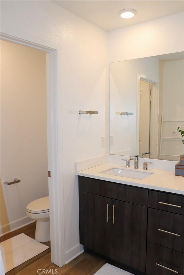 bathroom featuring wood-type flooring, toilet, and vanity