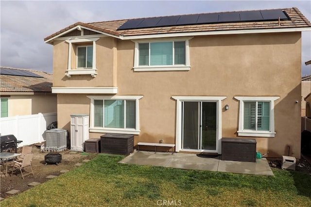 rear view of property featuring a lawn, solar panels, a patio area, and central air condition unit