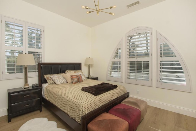 bedroom featuring an inviting chandelier and light hardwood / wood-style floors