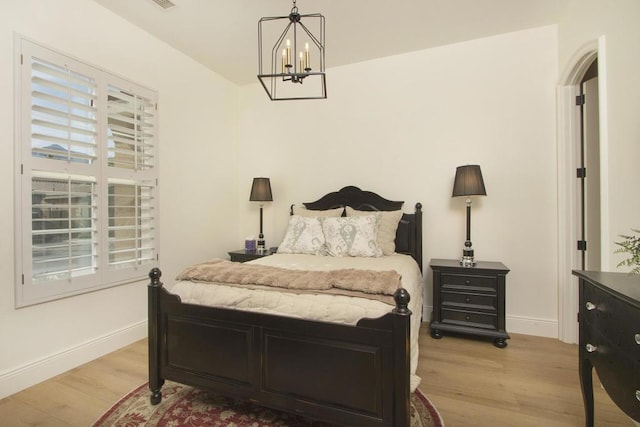 bedroom with a notable chandelier and light wood-type flooring