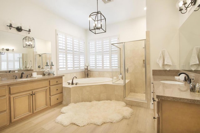 bathroom featuring wood-type flooring, plus walk in shower, vanity, and a wealth of natural light