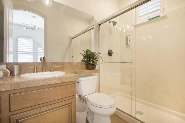 bathroom with a shower with door, vanity, a chandelier, and toilet