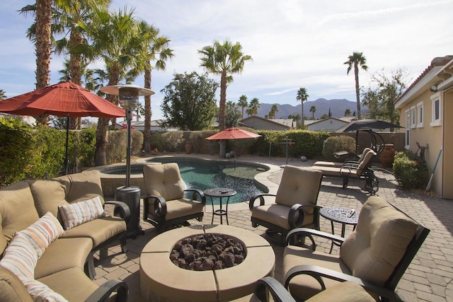 view of patio featuring a mountain view, a fenced in pool, and an outdoor living space with a fire pit