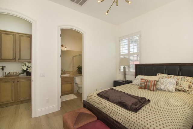 bedroom with sink, a notable chandelier, light hardwood / wood-style flooring, and ensuite bathroom