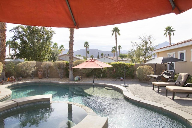 view of pool with an in ground hot tub, a mountain view, and a patio