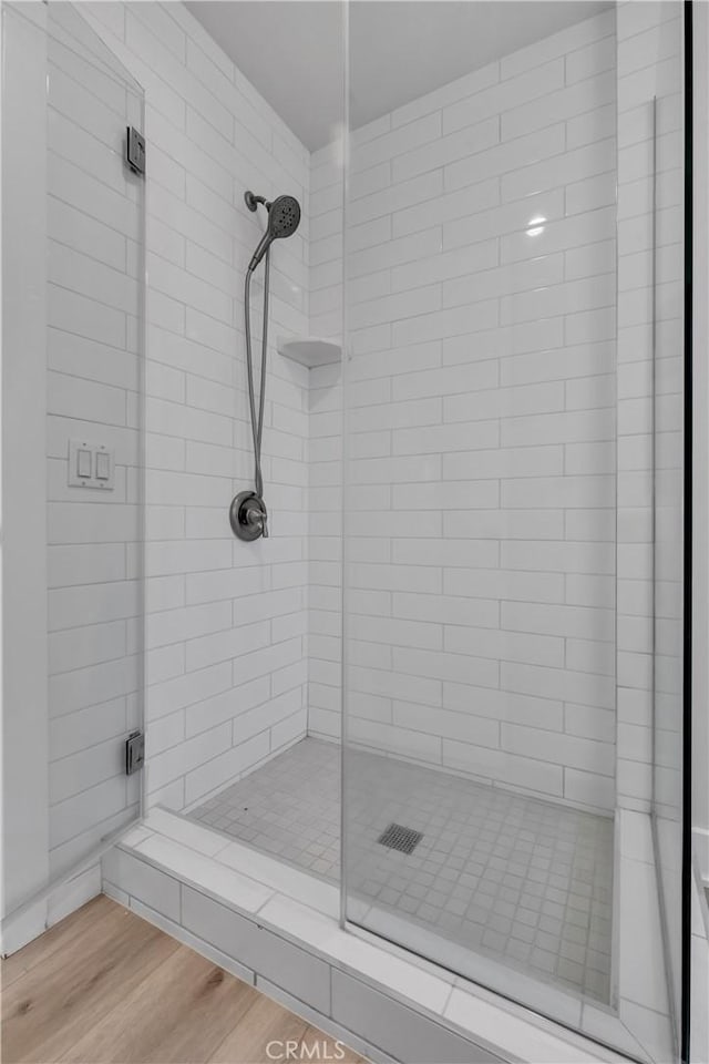 bathroom with wood-type flooring and a shower with shower door