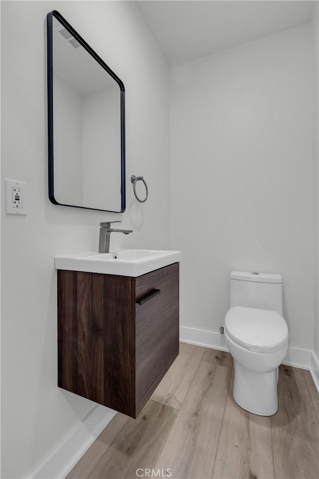 bathroom featuring vanity, wood-type flooring, and toilet