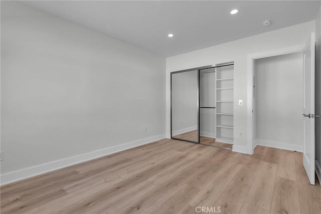 unfurnished bedroom with a closet and light wood-type flooring