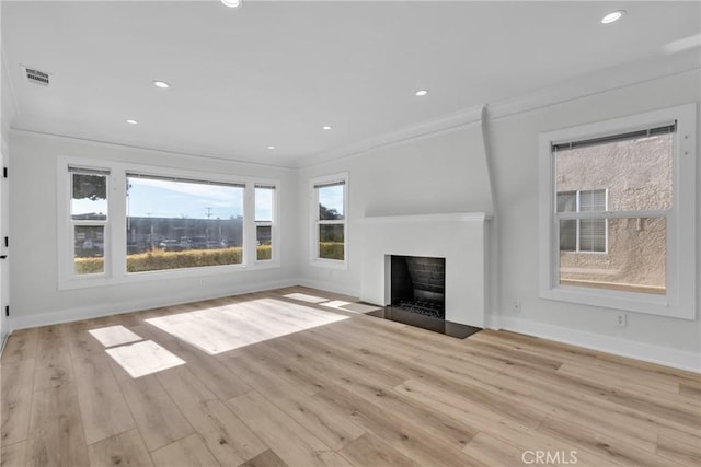 unfurnished living room featuring ornamental molding and light wood-type flooring