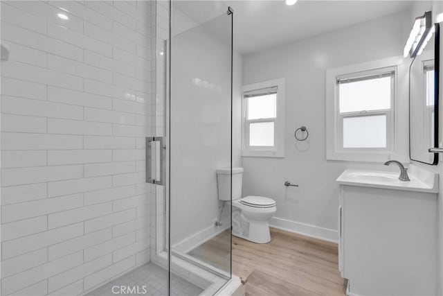 bathroom featuring vanity, toilet, a shower with door, and hardwood / wood-style floors