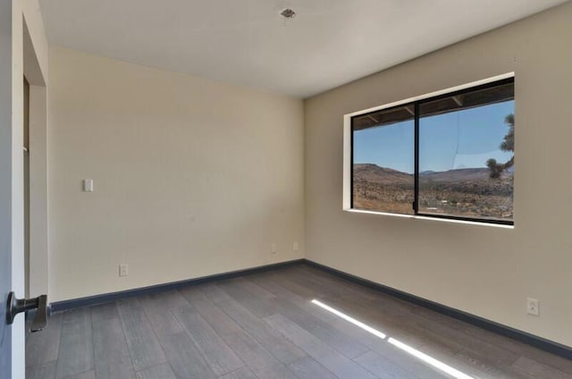 unfurnished room featuring hardwood / wood-style floors and a mountain view