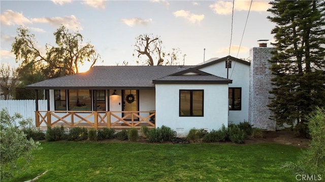 back house at dusk featuring a yard