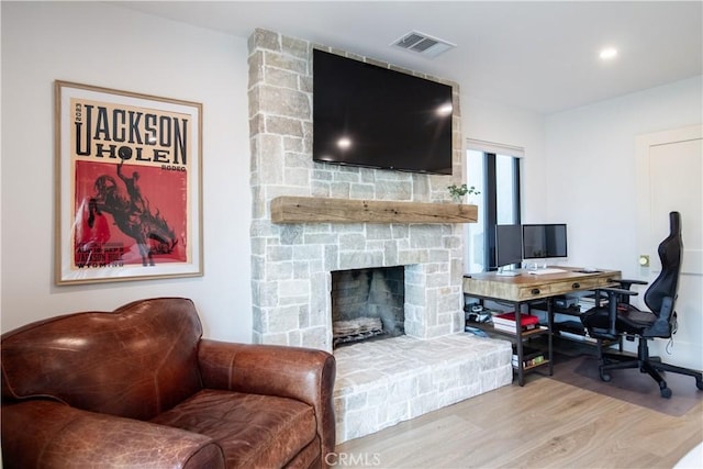 living room featuring hardwood / wood-style flooring and a stone fireplace